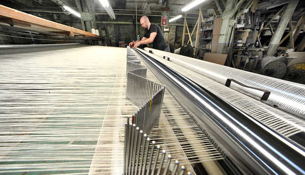 Rene Cote looks for a break in the line on the slasher machine at Maine Heritage Weavers in Lewiston. | RUSS DILLINGHAM/SUN JOURNAL