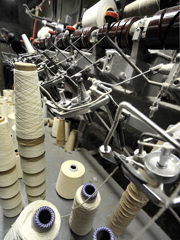 After used bobbins are swapped out for full ones, they are sent downstairs to be spliced together on this machine to create full ones. | RUSS DILLINGHAM/SUN JOURNAL