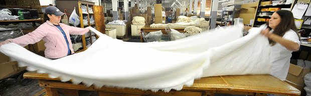 Sue Valonis, right, and her daughter Michelle Boilard fold an Abigail Adams bedspread at Maine Heritage Weavers in Lewiston. | RUSS DILLINGHAM/SUN JOURNAL