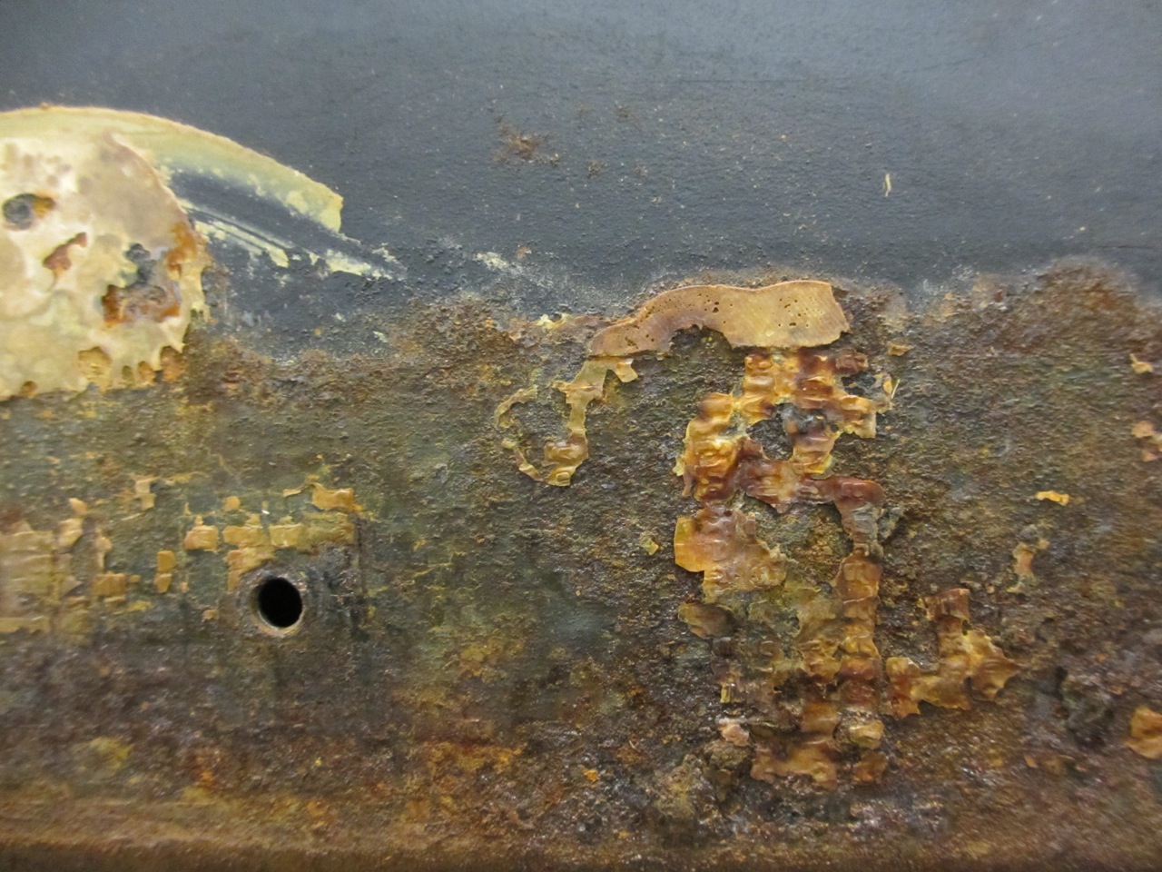  The chassis has a lot of rusted spots that we need to remove before putting the new underbelly sheet on. This picture shows the mix of rust and old glue that was used to put on the original underbelly wrap. 