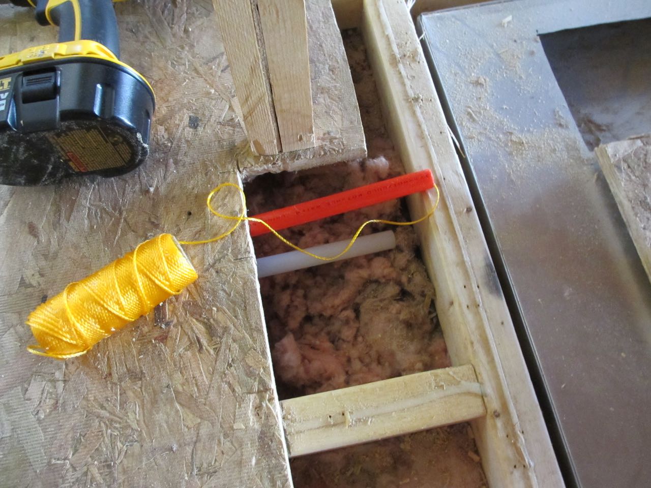 We placed two plastic pipes underneath the subfloors to help guide the heater electrical cords to where the thermostat will be. We put a string in one end of the pipe.