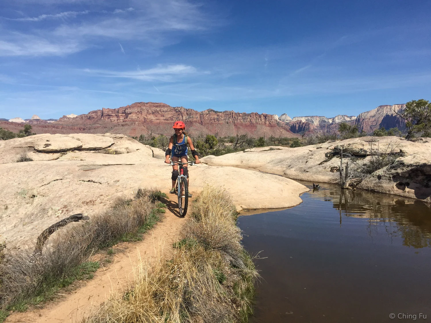 Sarah riding next to a pond that randomly shows up on the trail. Yes, that's Zion in the background.