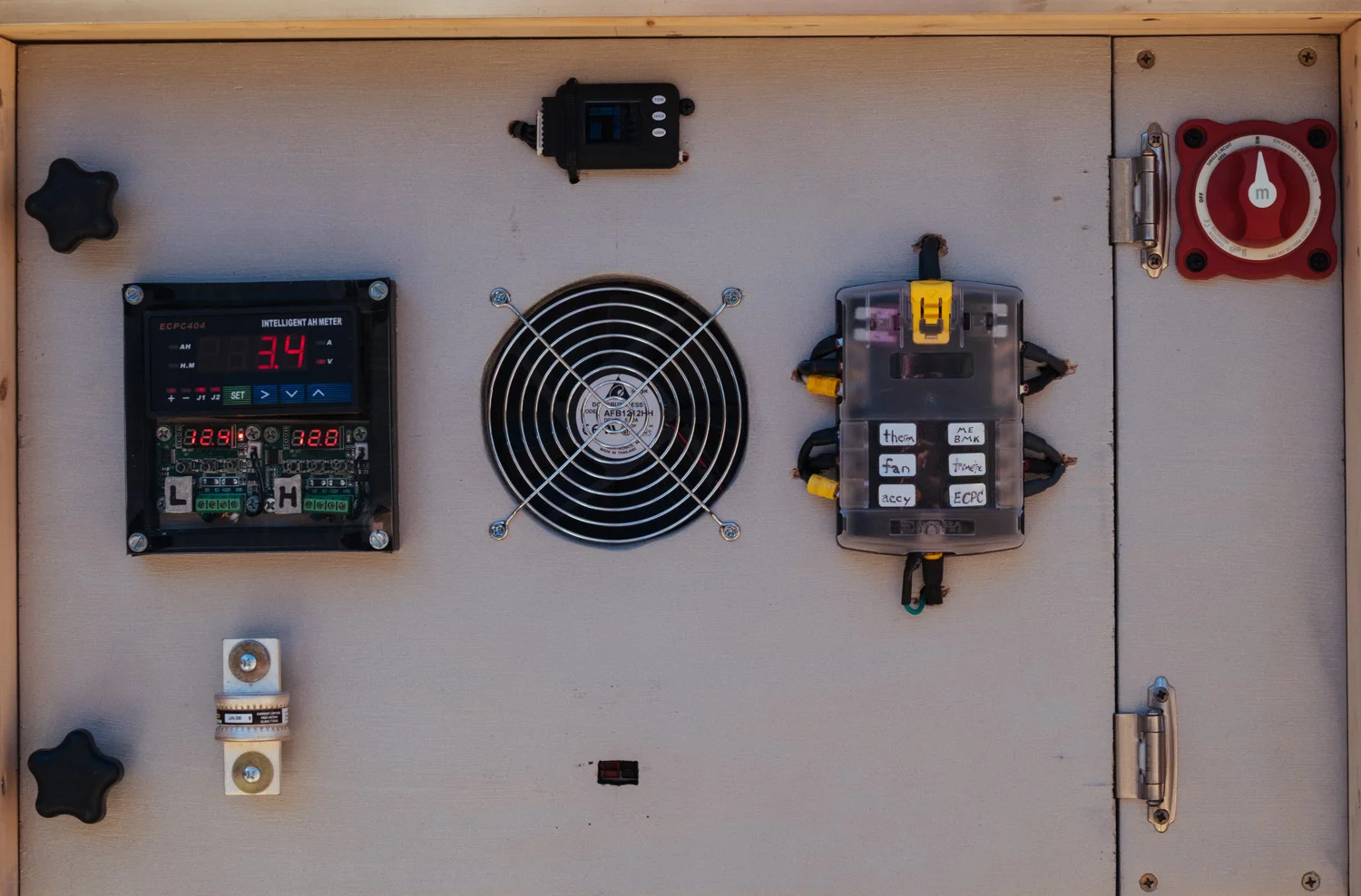 This is the front view of the updated "BMS panel" with (left to right): relay controller, thermostats, cell voltage monitor, cooling fan, fuse block, and battery disconnect switch. The spare fuse doubles as a handle.