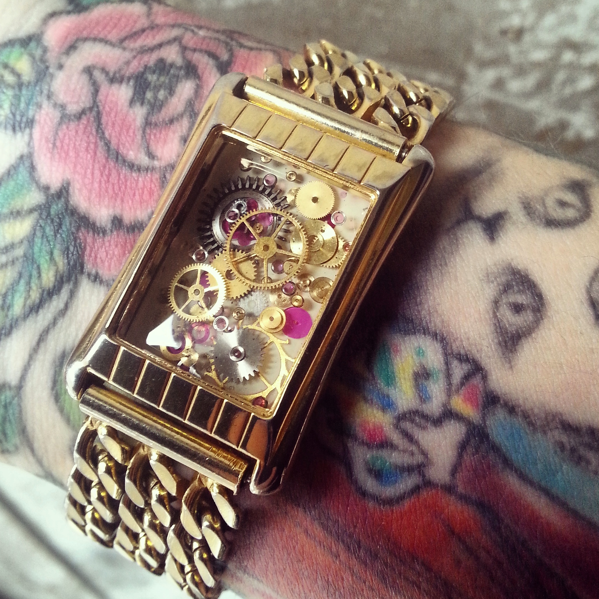 This vintage watch has been gutted and revamped into a stylish one of a kind bracelet containing multiple layers of resin cast watch parts over a hand painted background.