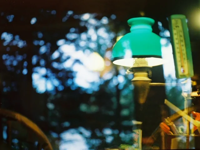 a reflection in the window of the light at grandma si's table and the glow of twilight outside, july 2017