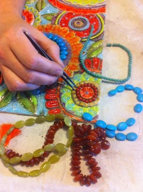 Setting in the semiprecious stones and beads to create the mosaic.