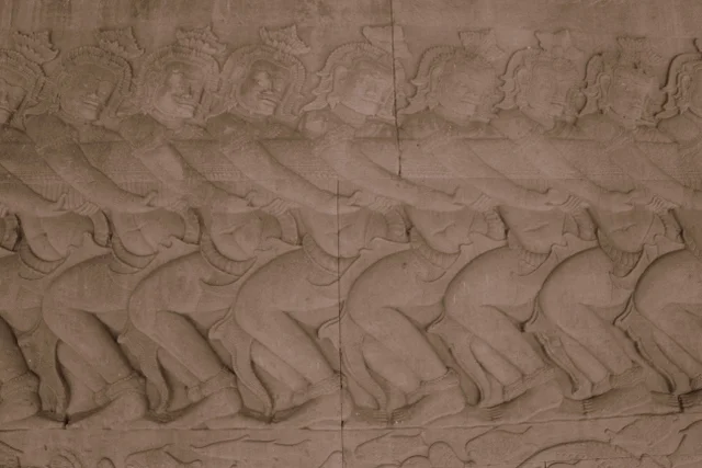 Carvings on an interior wall of Angkor Wat telling the central origin story of Hinduism, where gods and demons churn "the ocean of milk" for a millennium to release the nectar of immortal life, called Amrita.