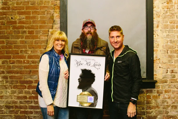 Crowder is honored with an RIAA Gold Certification plaque for David Crowder*Band's digital single "How He Loves" with sixstepsrecords' Shelley Giglio and Mike McCloskey.
