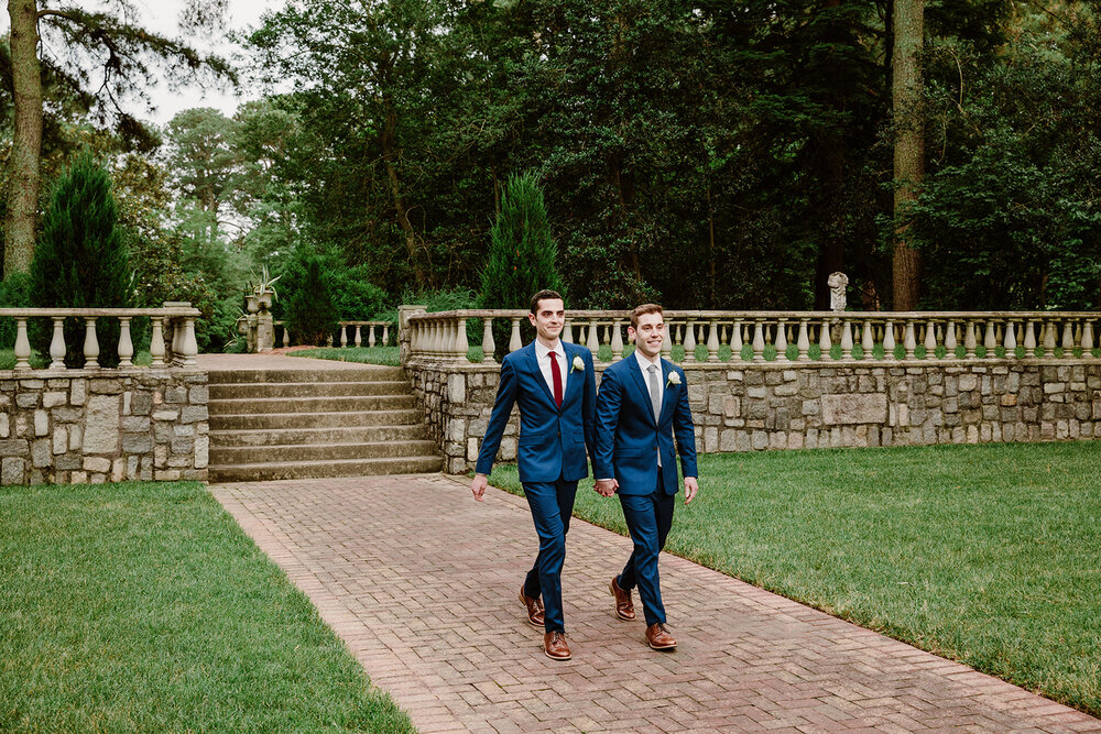  Two grooms walking down the aisle together. Vegan wedding at the Norfolk Botanical Gardens, Norfolk, VA. Rose garden and plant inspired wedding on the first day of Pride month. 