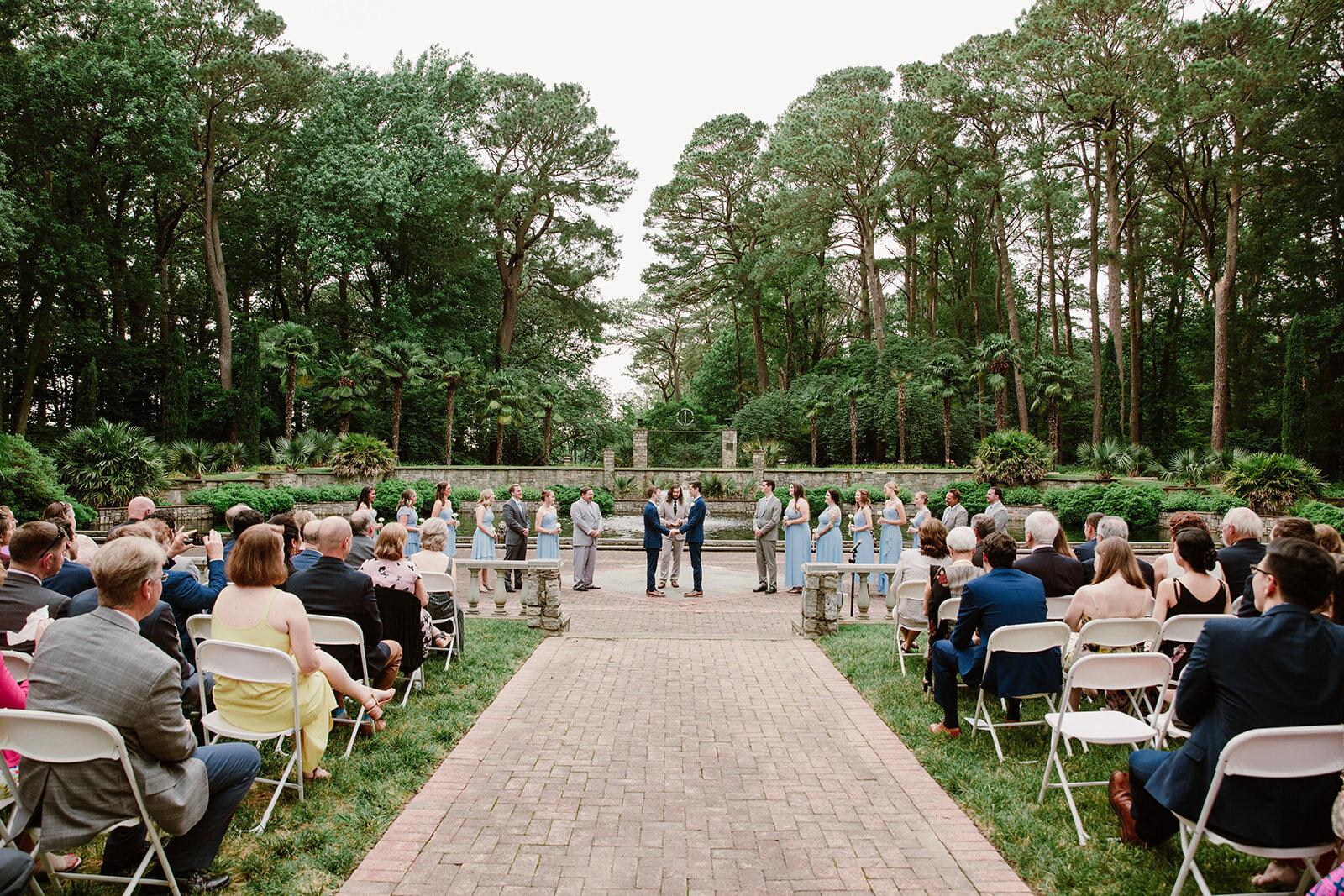  Two grooms walking down the aisle together. Vegan wedding at the Norfolk Botanical Gardens, Norfolk, VA. Rose garden and plant inspired wedding on the first day of Pride month. Sarah Mattozzi Photography. 