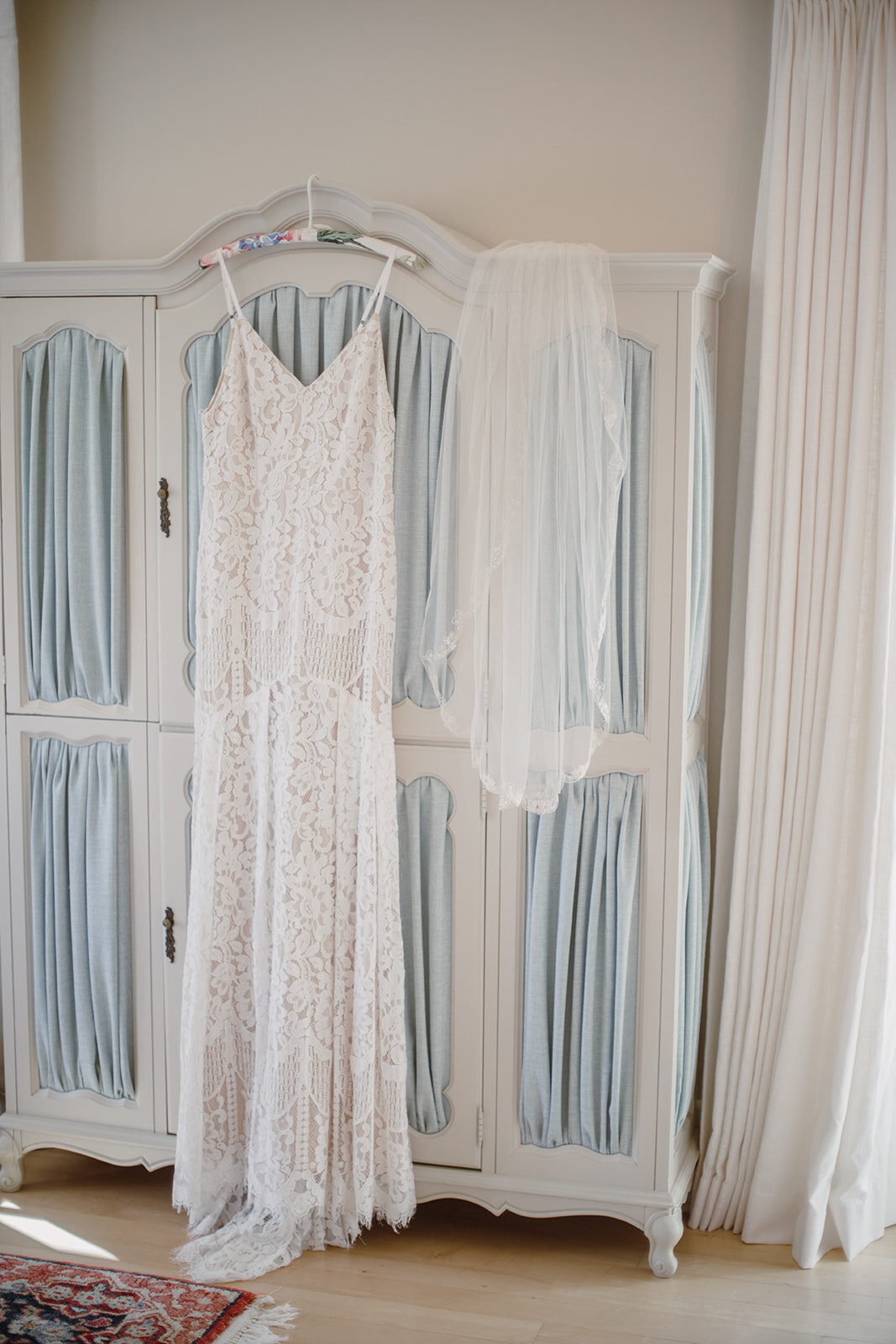 Dress hanging on a blue wardrobe with a veil. Intimate Italian villa elopement at Monteventoso in Madison, Virginia. 