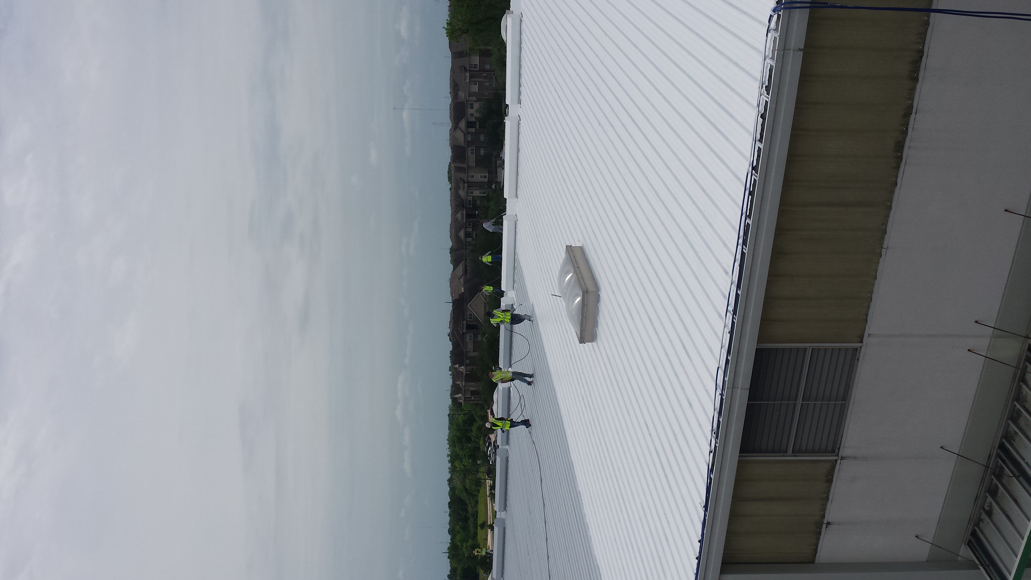 Metal roof coating in process. White elastomeric roof coating.