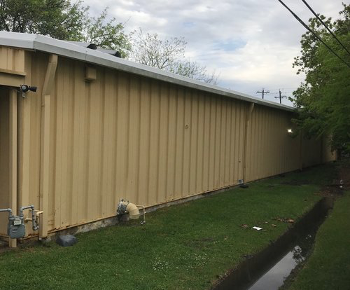 Metal building rusting wall panels before being replaced with a hidden fastener panel system