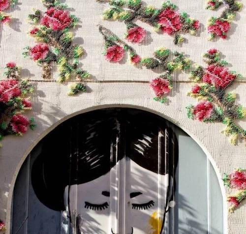 The Artist is Raquel Rodrego . You can read more about her giant delicate cross-stitch flowers all over Madrid here .