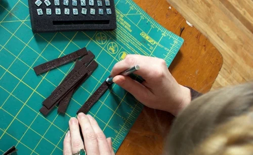 Hand stamping my name on repurposed leather.