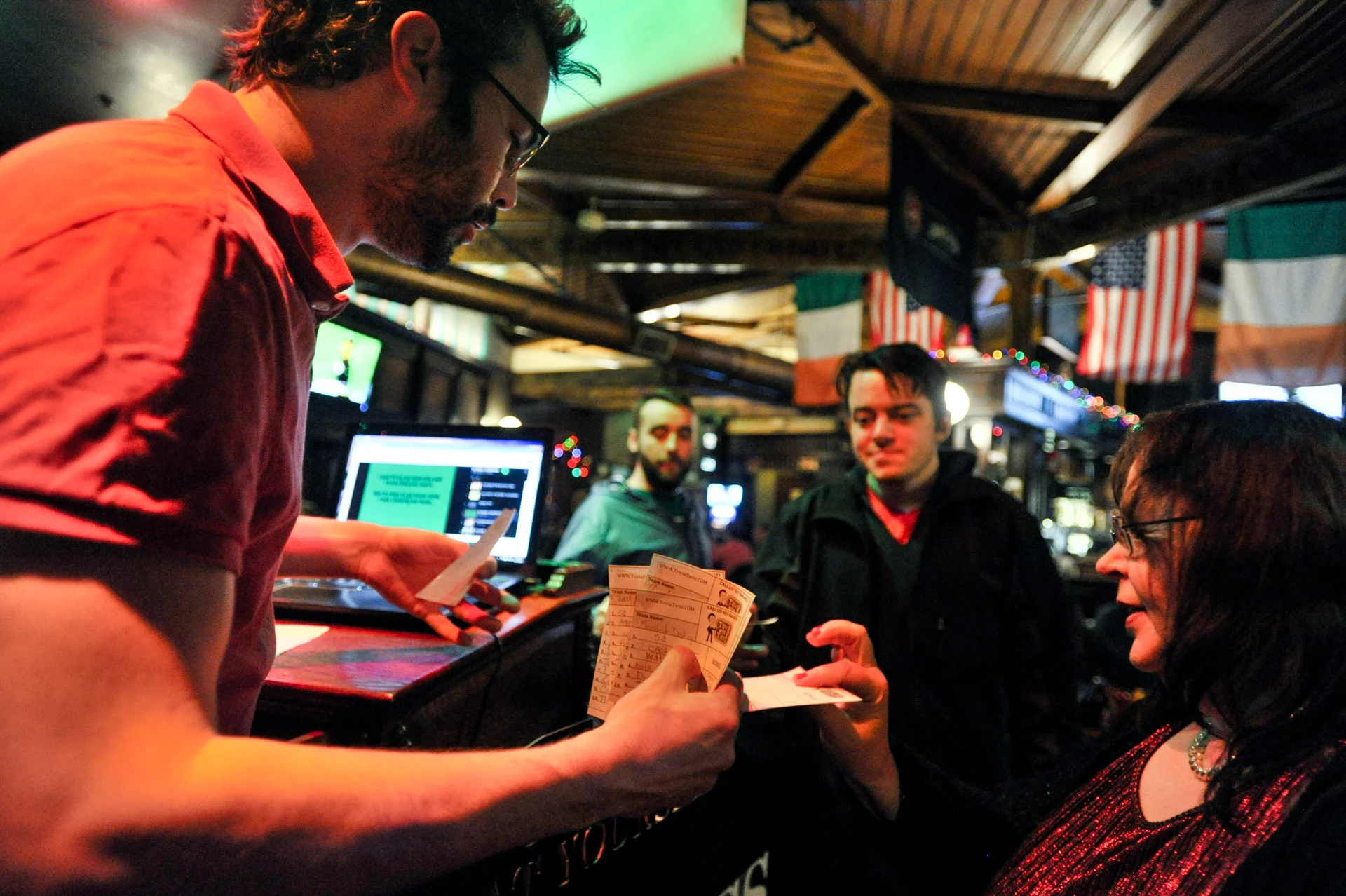 Trivia players hand in their answer cards for scoring by Trivia with a Twist host Mike Hilinksi on December 21, 2015, at the Dublin Pub in Dayton, Ohio. The winner of each round receives Coors Light pint glasses, provided by Coors' sponsorship of the event. (©2015 Sarah Stier for Dayton City Paper)
