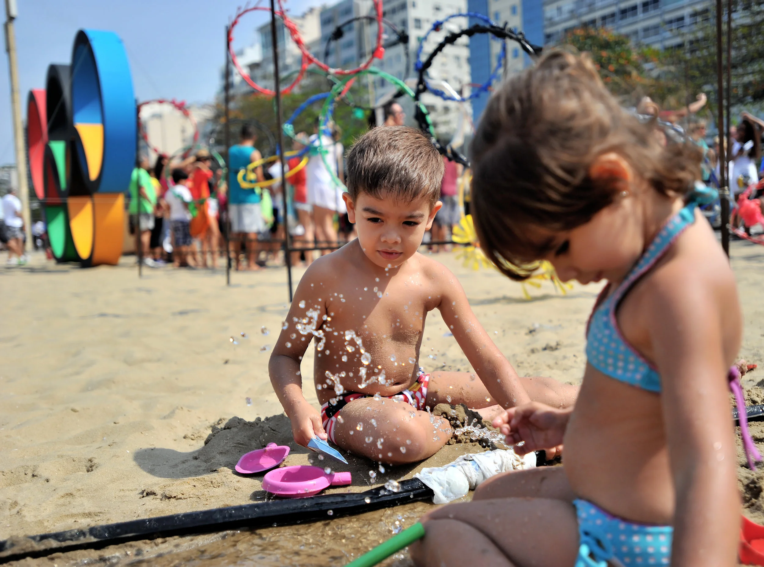 Erik Leal Temporal, 4, and his sister Melissa, 3, of Rio de Janeiro, play in the sand near the Olympic Rings at Copacabana Beach in Rio de Janeiro, Brazil, on August 7, 2016. (Sarah Stier | Ball State at the Games)