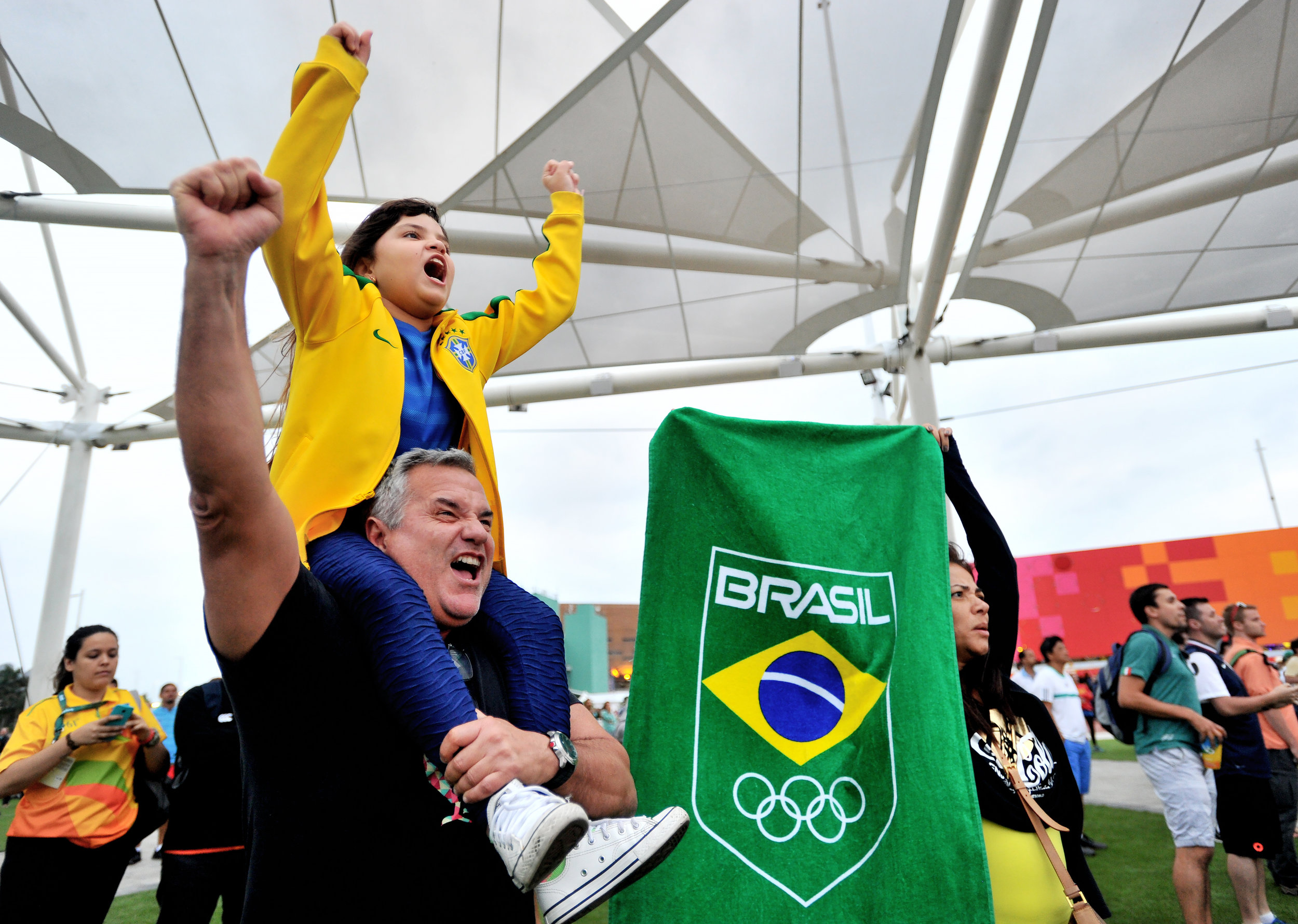 Olive Costa and his daughter Victoria, 7, cheer while his wife, Antomia Costa, holds up a Brazilian flag in support of a Brazilian judo player at the Olympic Park in Rio de Janeiro, Brazil, on August 8, 2016. (Sarah Stier | Ball State at the Games)