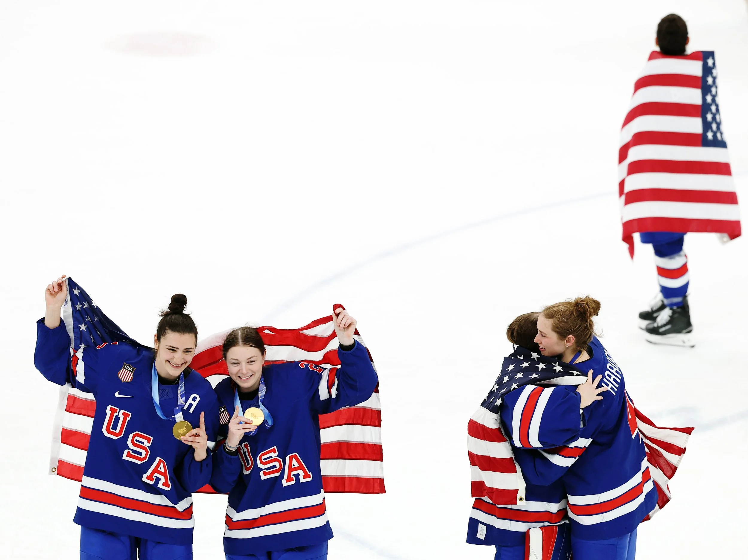  Megan Keller #5, Lee Stecklein #2, Aerin Frankl #31, and Caroline Harvey #4 of Team United States celebrate with flags after winning the Women's Gold Medal match against Canada on day thirteen of the Milano Cortina 2026 Winter Olympic games at Milan