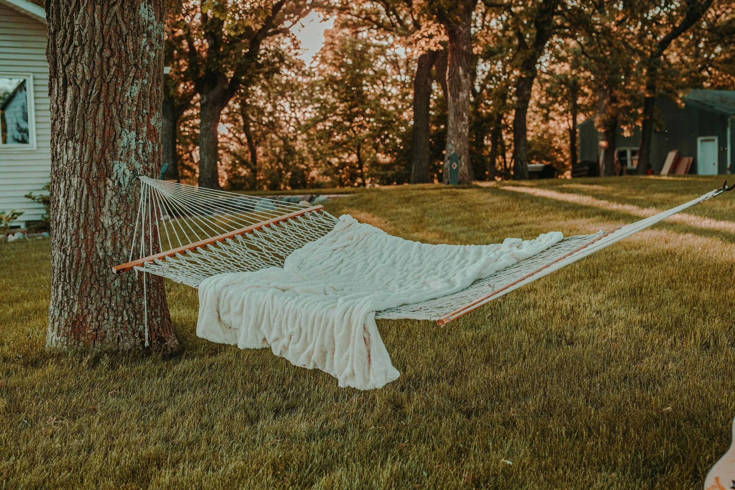 An empty hammock with a blanket draped across it.