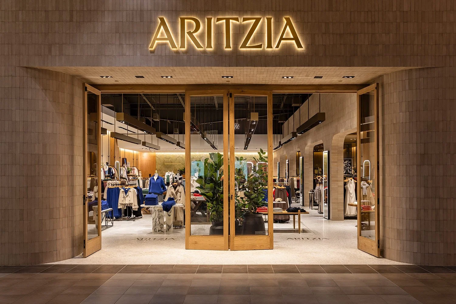  Architectural exterior photography of the Aritzia retail boutique, showcasing luxury storefront design, warm interior lighting, and upscale commercial branding for retail design portfolios 
