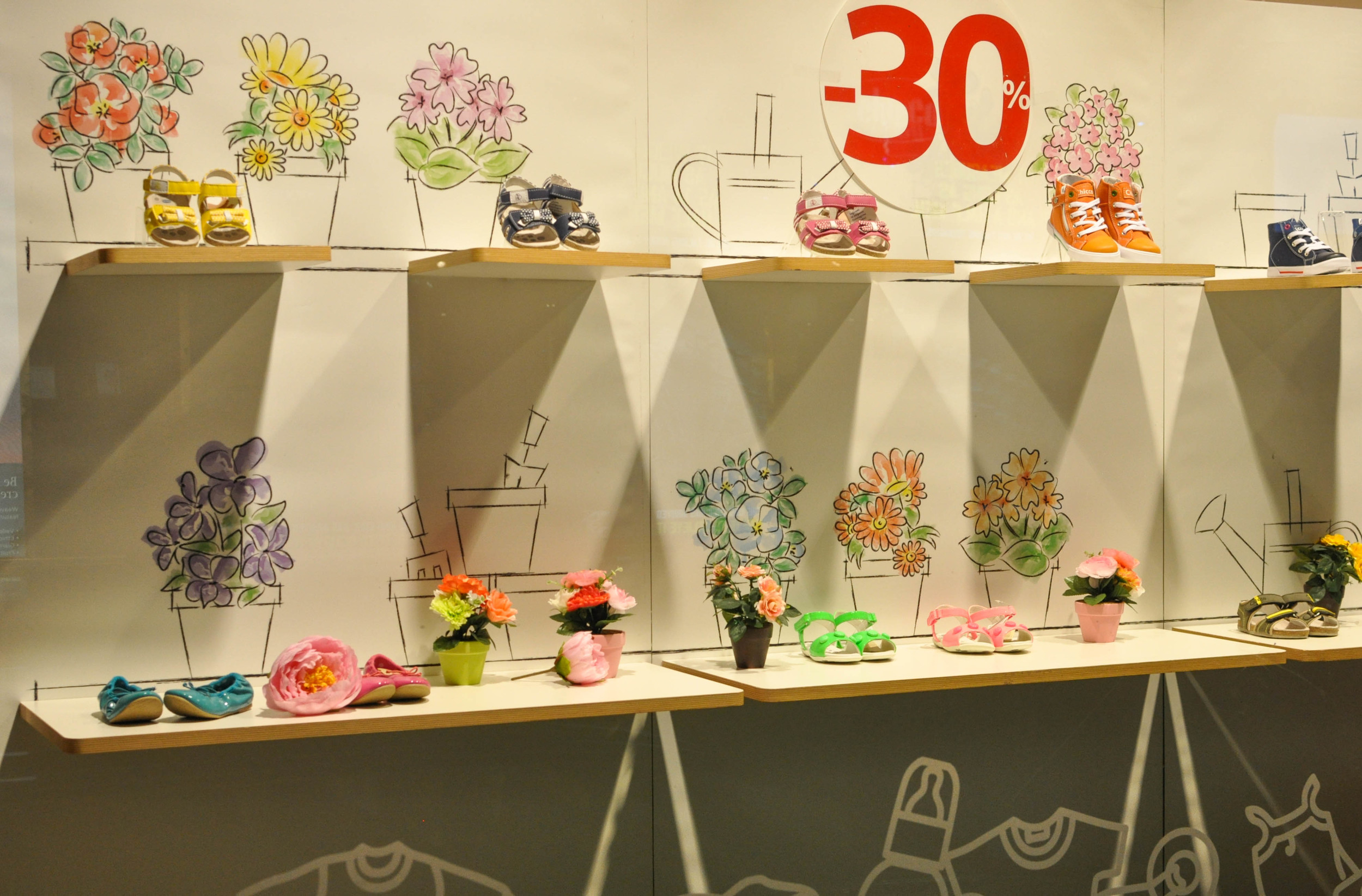 CHICCO Chicco's summer shoe display was supported by simple yet cute hand-drawn art depicting a spring/summer garden scene. The material used was thick butchers-type paper in panels. Coloured pots of fake flowers also enlivened the scene.