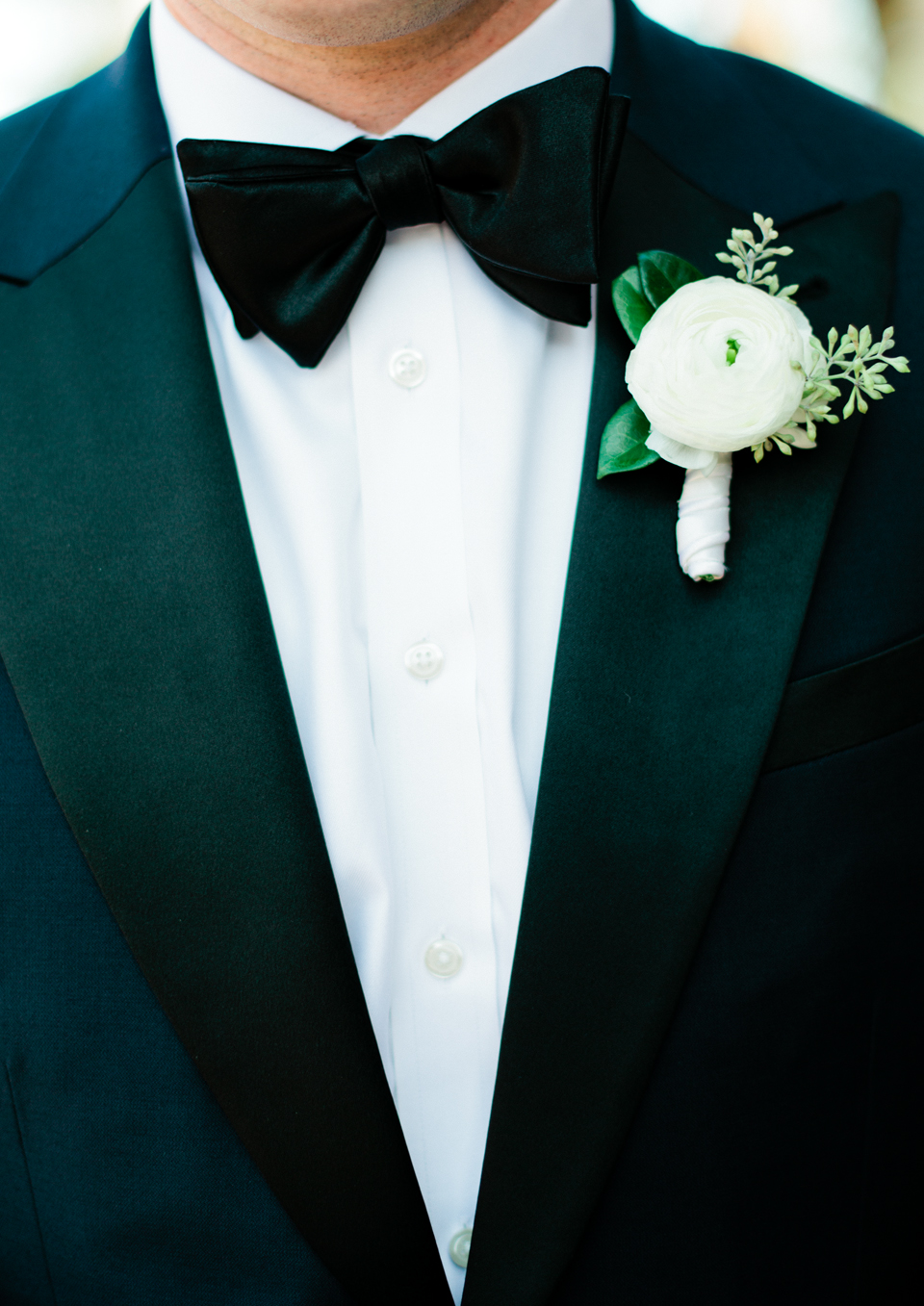 Picture of a groom wearing a black tuxedo with a white flower boutonniere at the TPC Sawgrass in Ponte Vedra, Florida 