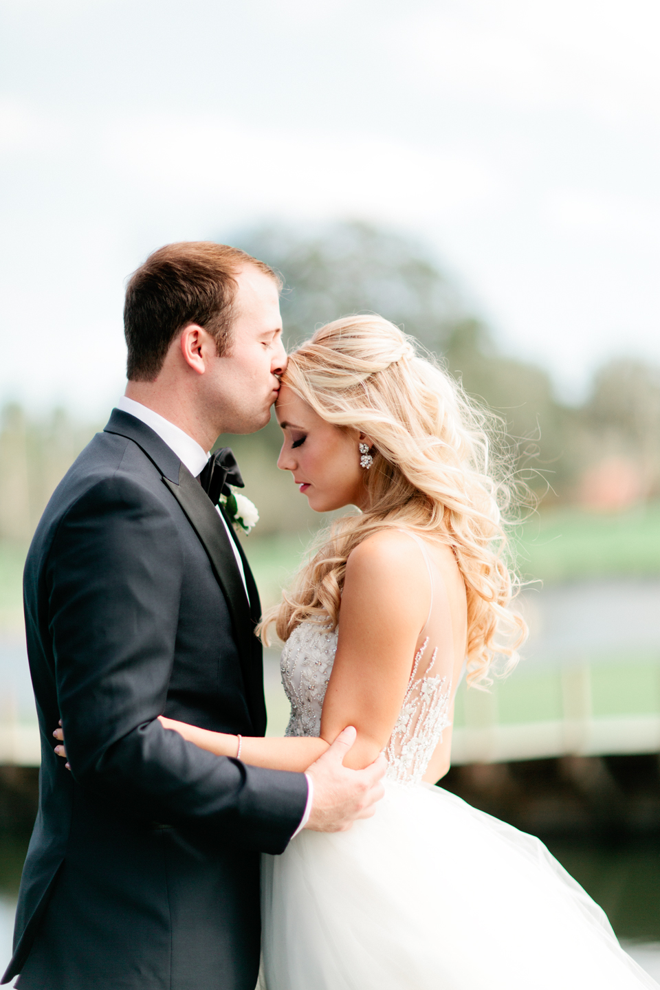 Image of a groom kissing the forehead of his bride on their wedding day at TPC Sawgrass in Ponte Vedra, Florida