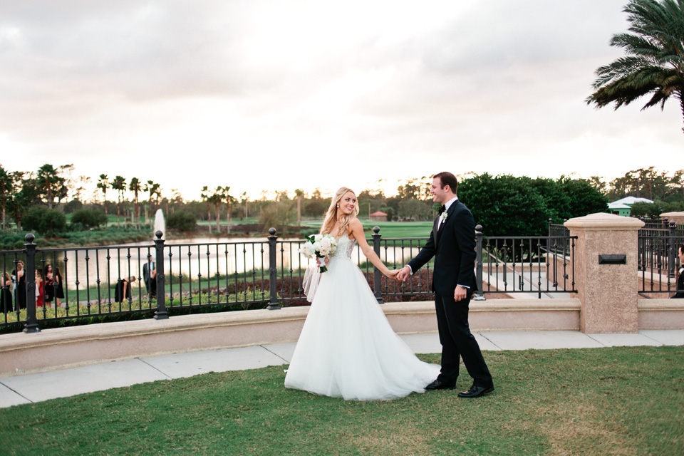 Image of a bride and groom walking hand in hand on their wedding day with the sun setting at TPC Sawgrass in Ponte Vedra, Florida