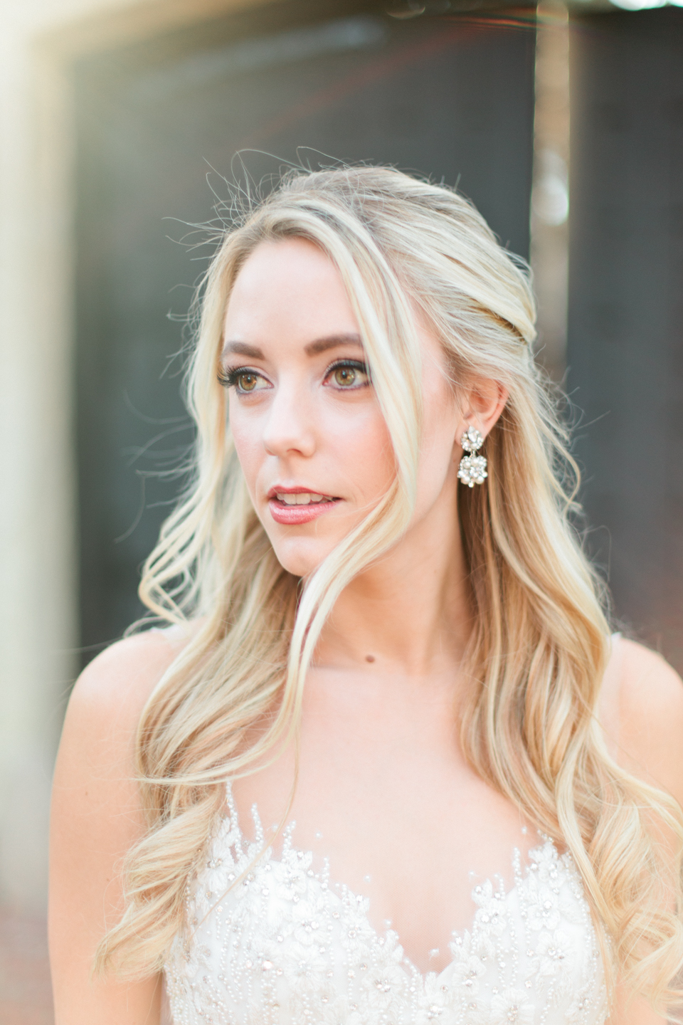 Image of a close up of a bride with her hair curled, diamond earrings and a Calvet Couture bridal gown.  She is in front of Epping Forest Yacht Club in Jacksonville, Florida