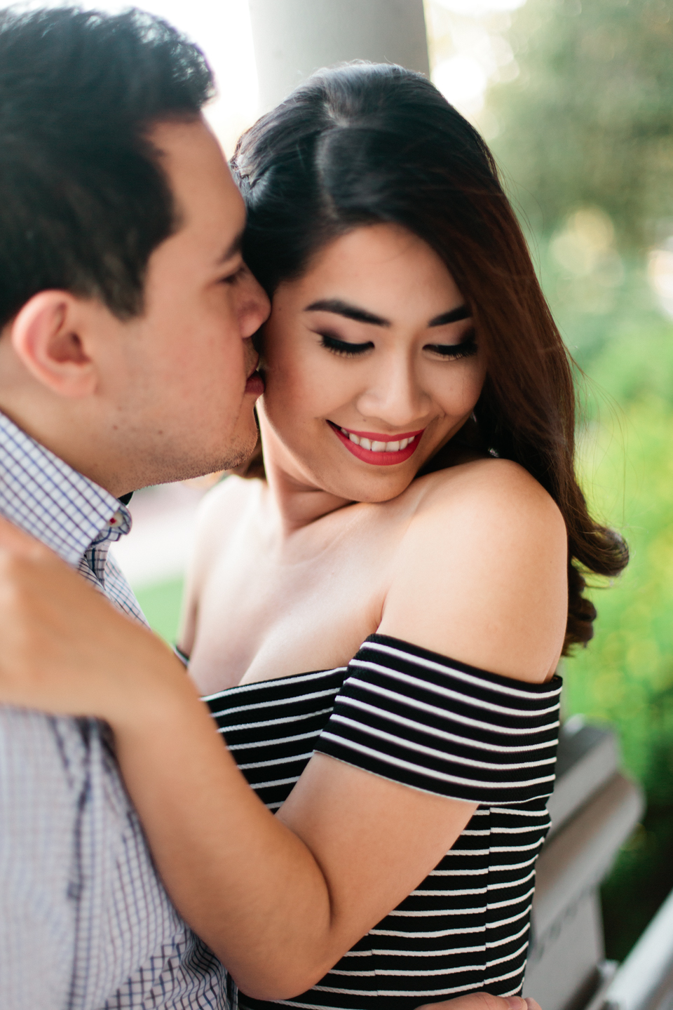 This is a picture of an engaged couple at the Henry B. Plant museum in Tampa, Florida.  He is kissing her cheek, she is looking away and smiling.