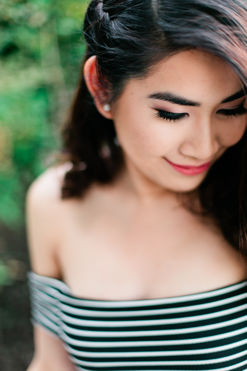 Image of a beautiful asian woman with dark hair, looking down and smiling.  Image is taken at the Henry B. Plant museum in Tampa, Florida.