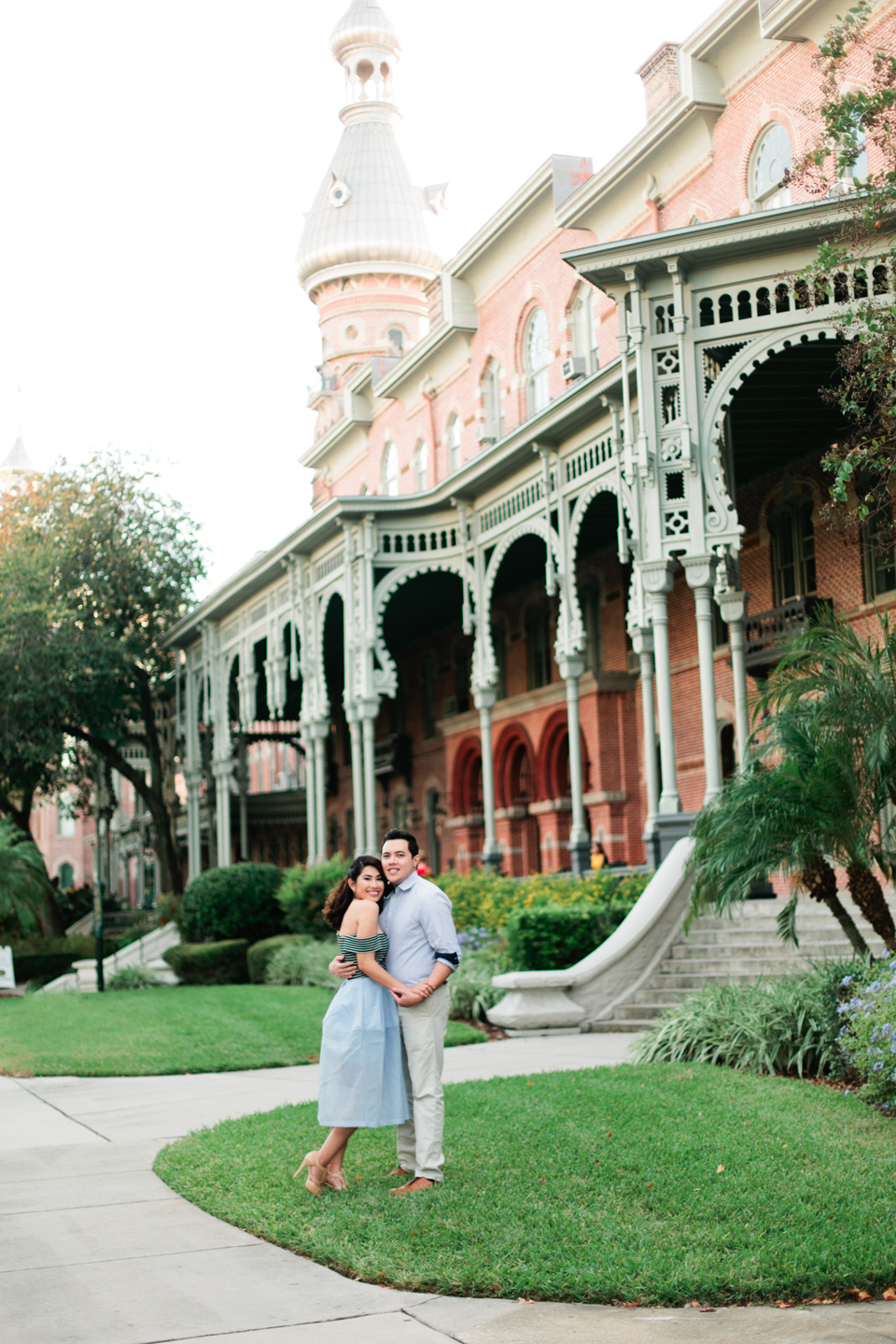Image of an engaged couple embracing in front of the Henry B. Plant museum in Tampa, Florida.