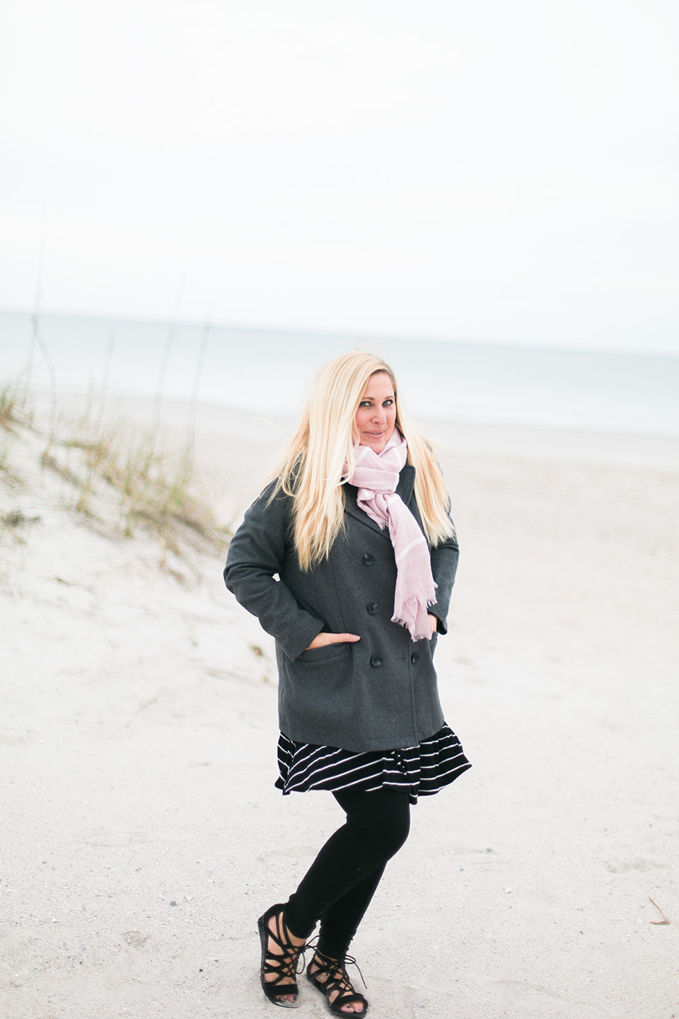 Picture of a woman in a coat and scarf on the white sand beach of the Atlantic coast at Omni Amelia Island Plantation Resort.