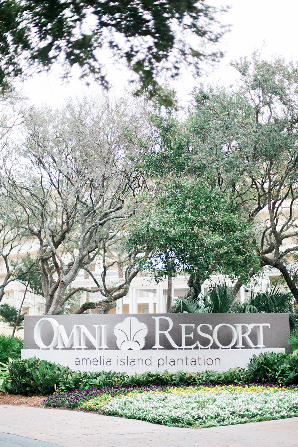 This is a picture of the entrance to the Omni Amelia Island Plantation Resort.  There is a sign with large letters, "Omni Resorts" with a flower in the middle of the sign.