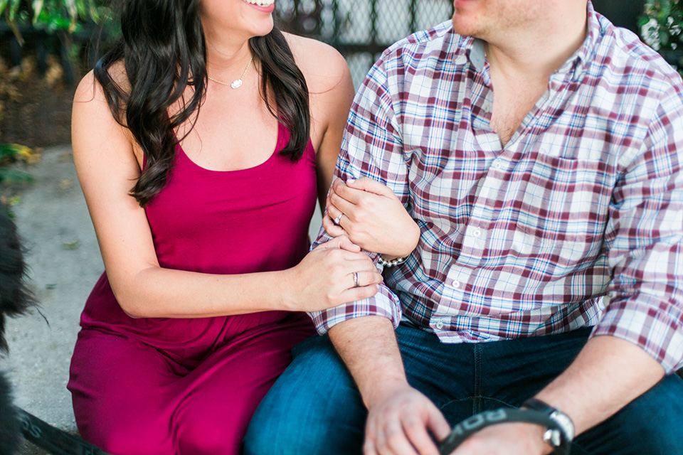 Image of an engaged couple linking arms and looking at each other lovingly.  They are both sitting on steps in front of a gate in downtown Orlando, Florida