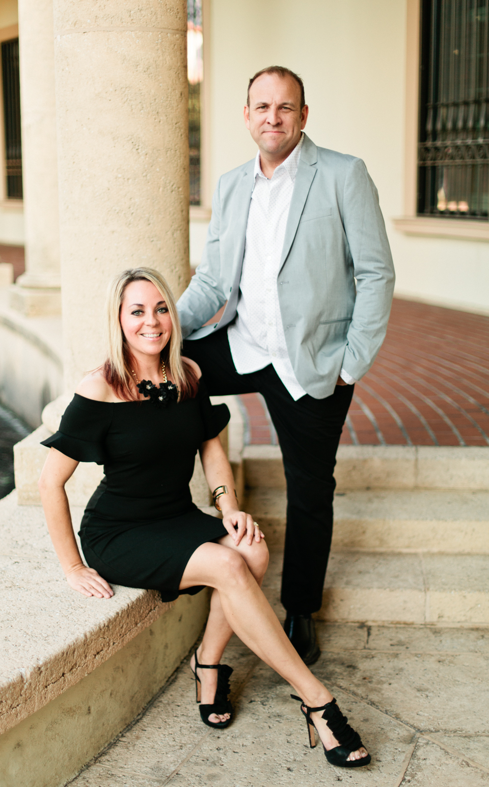 Image of a couple at the Museum of Fine Arts downtown St. Pete.  The woman is sitting with a black dress and the man is standing beside her in a sportscoat.