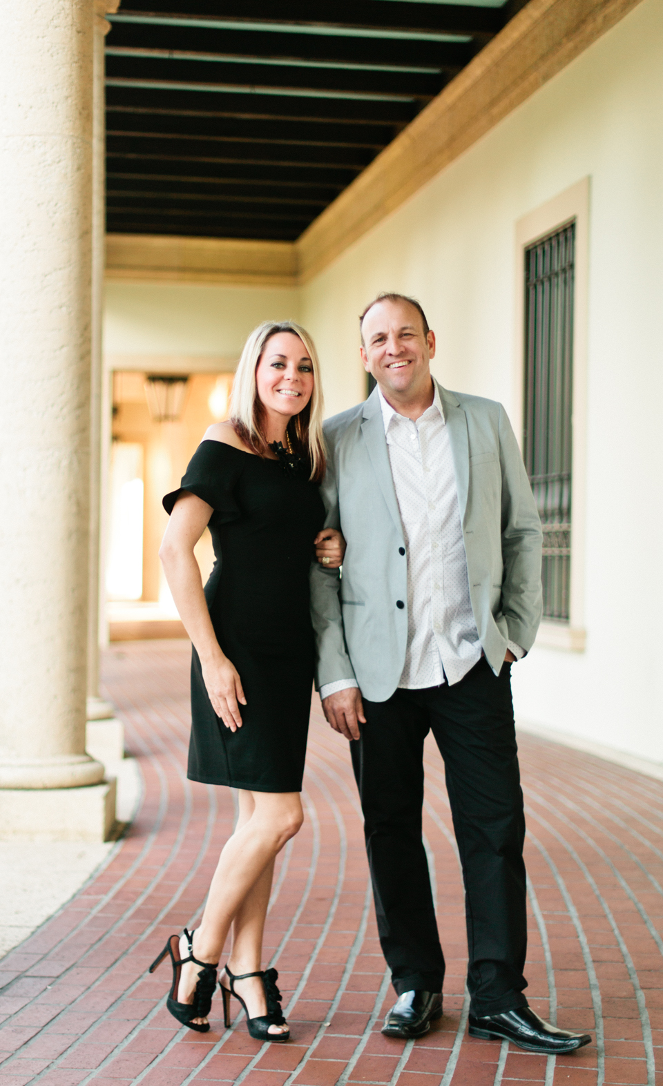 Image of a couple standing in front of the Museum of Fine Arts downtown St. Pete.  The woman is in a black short dress with ruffled sleeves and the man is wearing a sportscoat.