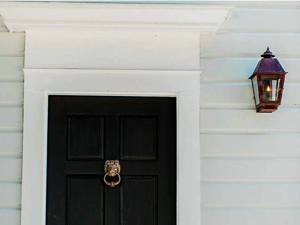 Image of a front porch with a black door and brass lion knocker.