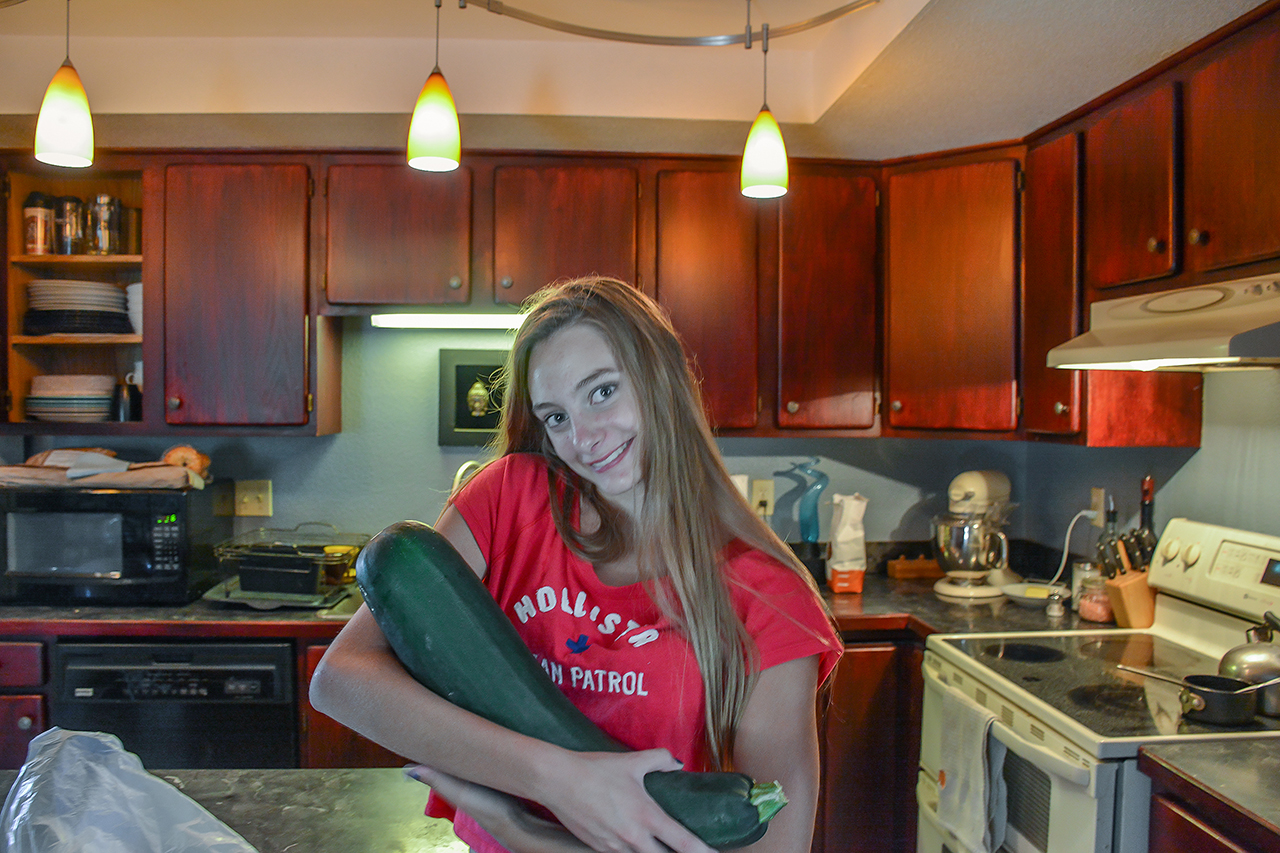 Kayla holding a zucchini the size of small baby