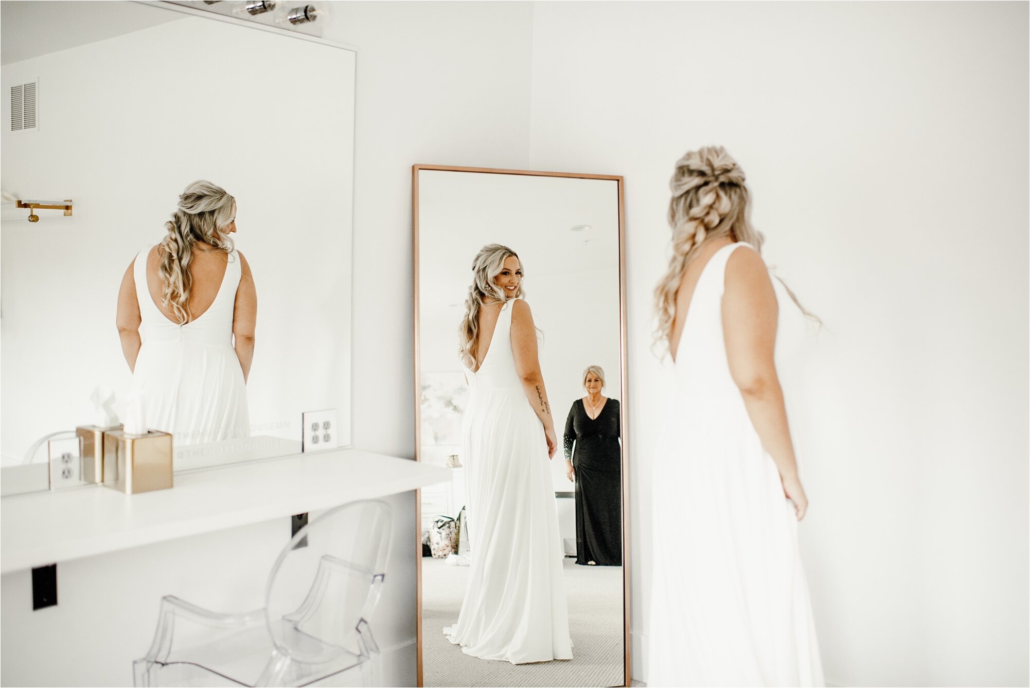  bride in dress, looking in mirror, with mom, on wedding day 