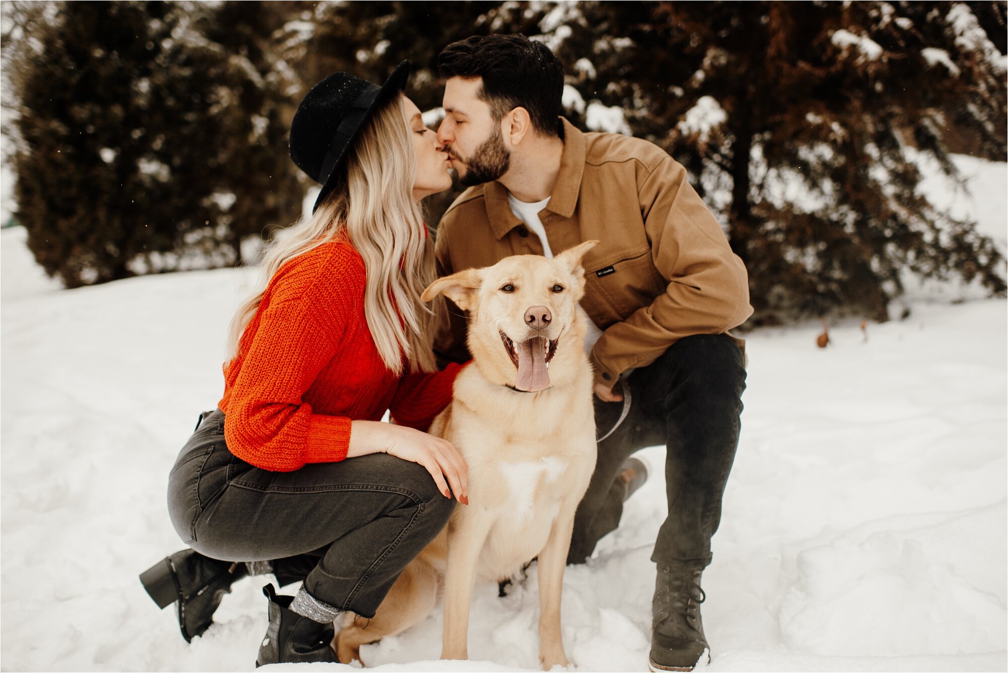  couple with dog in snow at theodore wirth regional park in minneapolis minnesota red sweater tan jacket bride groom engagement 