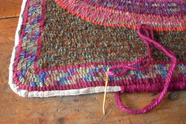 This is my preferred method of binding. The linen edge is rolled over cotton clothes line, basted in place and then whipped with wool yarn.