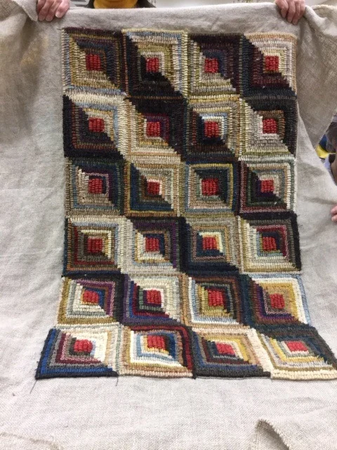 Lin Keller, a quilter and rug hooker, finished her log cabin design rug. Isn't it gorgeous? It looks like sunlight is streaming across it.