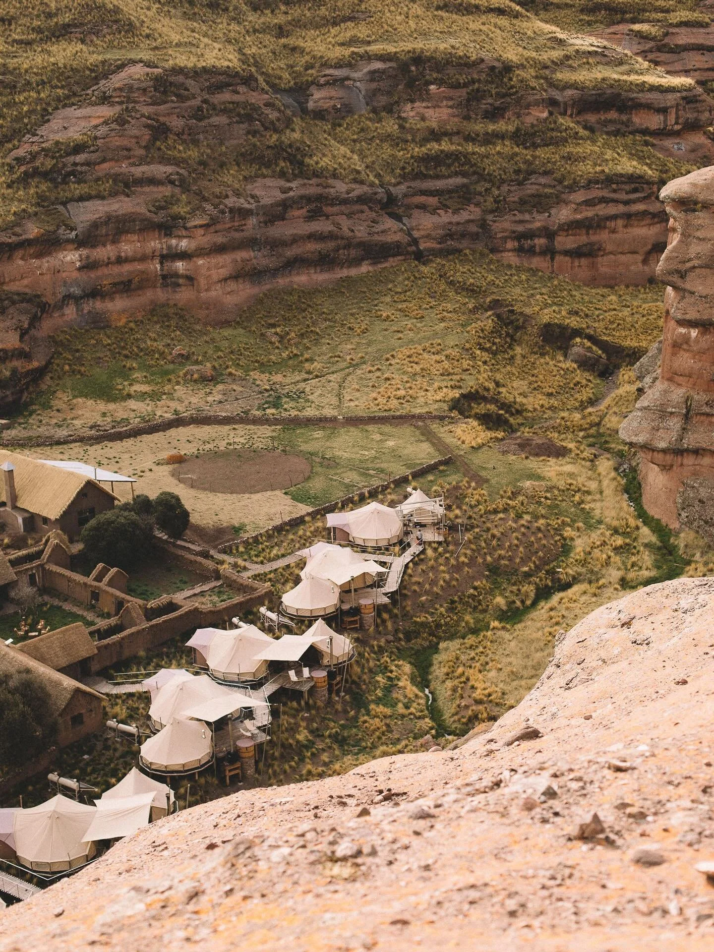 Set within the high-altitude plains of southern Peru, Tinajani Luxury Camp unfolds across a landscape shaped by time and erosion. Towering red rock formations rise from open grasslands, sculpted into arches, caves, and narrow passageways that feel bo