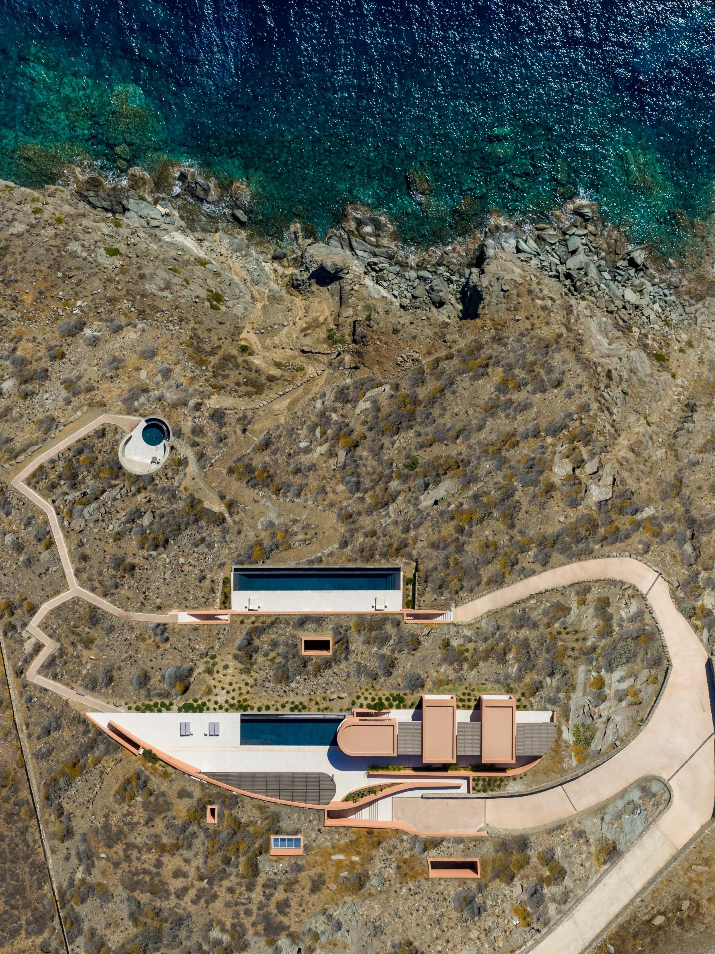 Set into the rugged coastline of Syros, OLEN Syros by ATENO Architecture Studio explores a quieter and more sculptural interpretation of Cycladic hospitality. The retreat is embedded directly into the rocky terrain, allowing architecture and geology 
