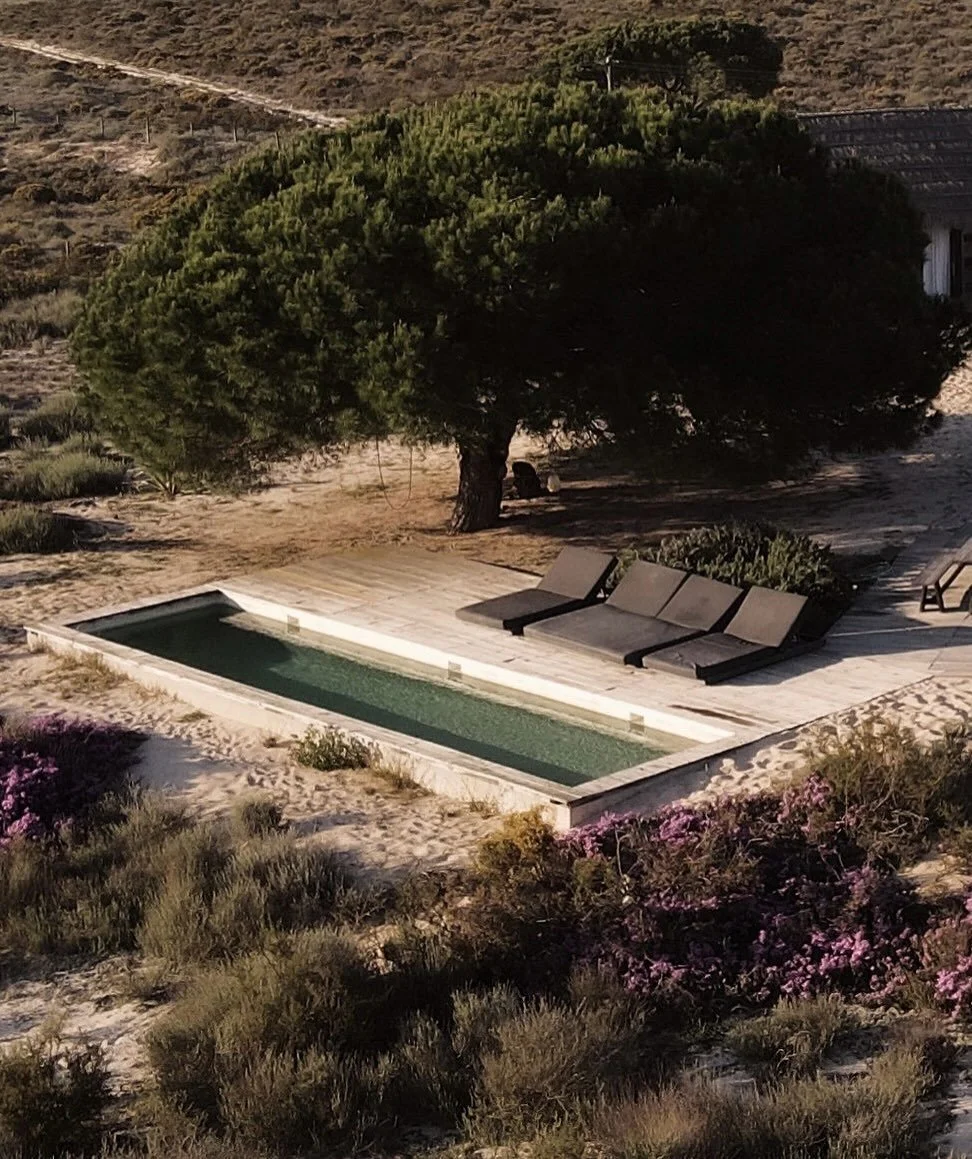 Casas na Areia sits within the wider dune landscapes of Comporta, where rice fields, pine forests, estuaries, and Atlantic sand systems create one of Portugal&rsquo;s most distinctive coastal environments. The geography is defined by shifting dunes s
