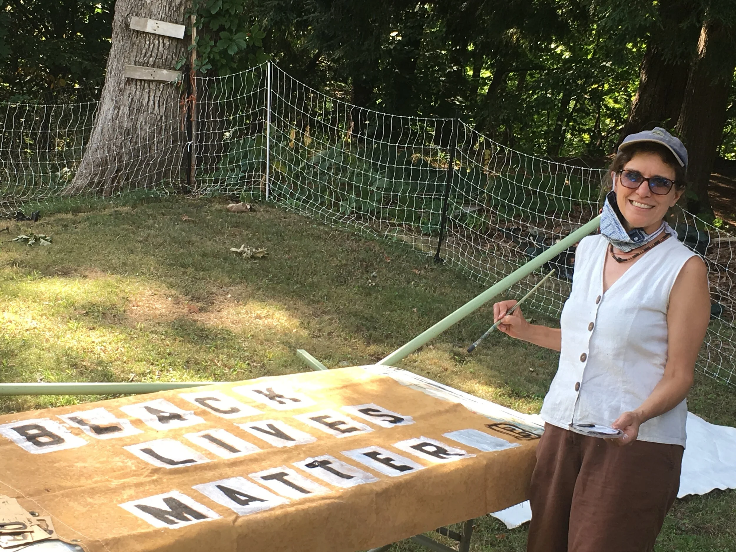 Person painting Black Lives Matter banner in yard