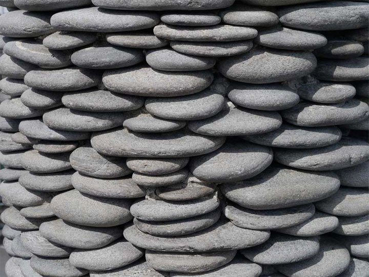  The column is encircled in pebbles that look as if they're precariously balanced on top of each other: they're smooth so you want to touch, but it looks risky!    