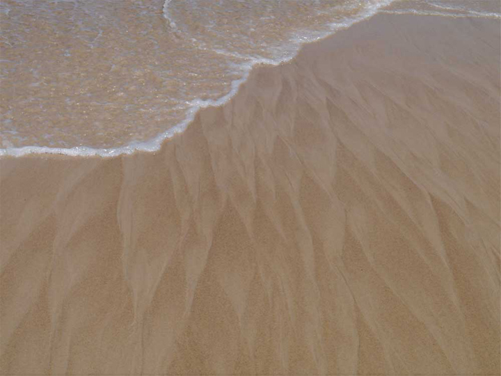 The softness of wet sand washed into braided wave patterns.